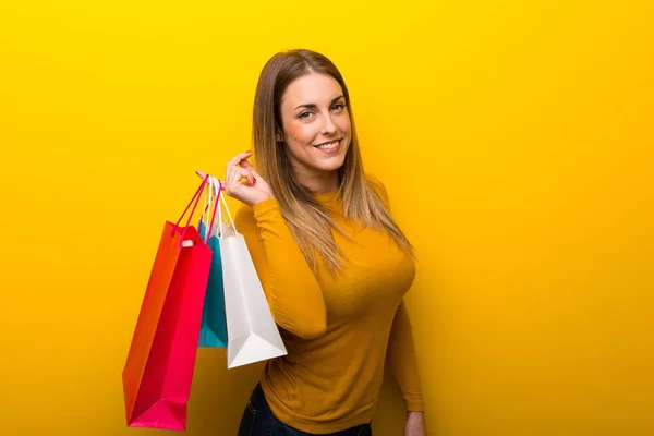 Genç Kadın Sarı Arka Planda Çok Alışveriş Torbaları — Stok fotoğraf