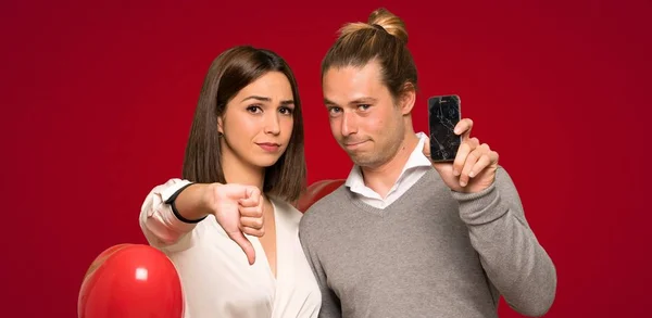 Couple in valentine day with troubled holding broken smartphone over red background