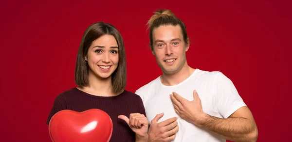 Couple in valentine day with surprise facial expression over red background