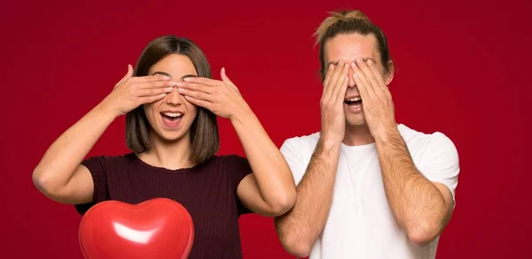 Pár Valentine Den Krycí Oči Rukama Nad Červeným Pozadím — Stock fotografie