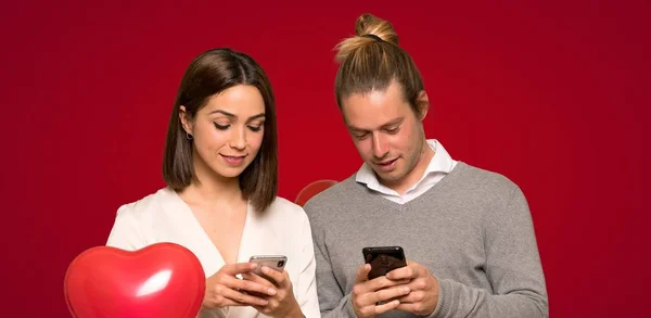 Pareja Día San Valentín Enviando Mensaje Con Móvil Sobre Fondo —  Fotos de Stock