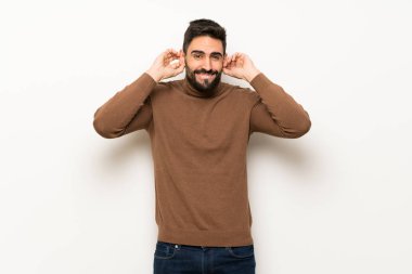 Beyaz duvar eller kulaklar kaplama yakışıklı adam. Hayal kırıklığı ifade