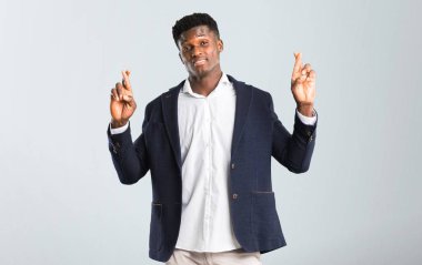 En iyi dilek ve geçiş parmakları ile ceket Afro-Amerikan yakışıklı. Bir dilek yapma. izole gri arka plan üzerinde