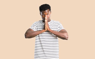 Çizgili gömlekli izole koyu sarı zemin üzerine bir şey için yalvaran koyu tenli adam