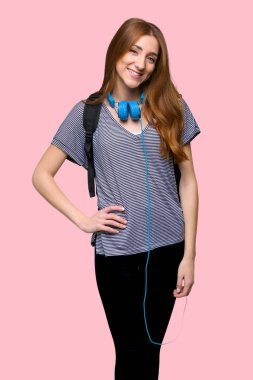 Silah, kalça ile poz ve izole pembe gülümseyen Kızıl saçlı öğrenci kadın