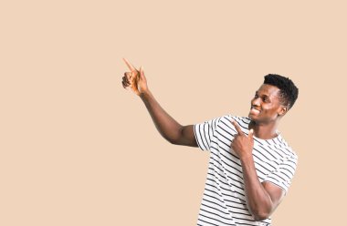 Harika bir fikir işaret parmağı ile işaret ve izole koyu sarı zemin üzerine ararken çizgili gömlek koyu tenli adam