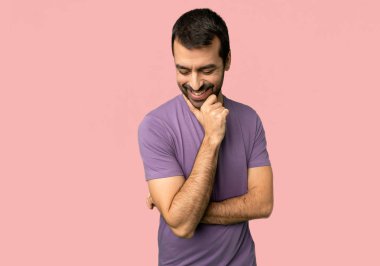 Yakışıklı adam izole pembe arka plan çeneme el ile bakıyor