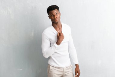 Genç afro Amerikalı adam dokulu gri duvara poz