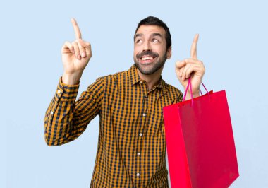 Adam alışveriş torbaları izole mavi zemin üzerine harika bir fikir işaret parmağı ile işaret ile