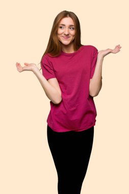 Elleri ve omuz izole Sarı zemin üzerine yükseltme sırasında şüpheleri genç Kızıl saçlı kız