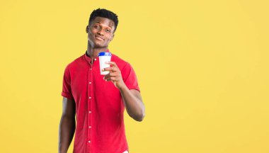 Paket servisi olan restoran kağıt bardak Sarı zemin üzerine sıcak kahve tutan genç Afro-Amerikan adam