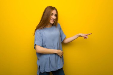 Yan yan pozisyonda sarı duvar arka plan işaret eden parmağa genç Kızıl saçlı kız