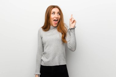 Kızıl saçlı kız beyaz duvar niyetinde üzerinde parmak kaldırma sırasında çözüm anlar