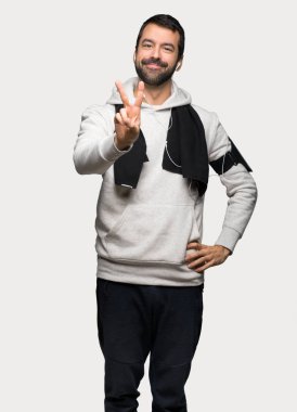 Gülümseyen ve zafer işareti izole gri arka plan üzerinde gösterilen spor adamı