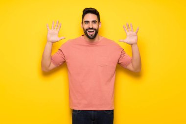 Sürpriz ve şok yüz ifadesi ile sarı duvarın üzerinden yakışıklı adam