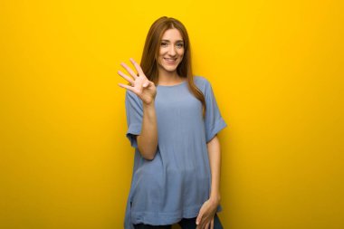 Mutlu ve sayım dört parmak ile arka plan sarı duvarın üzerinden genç Kızıl saçlı kız