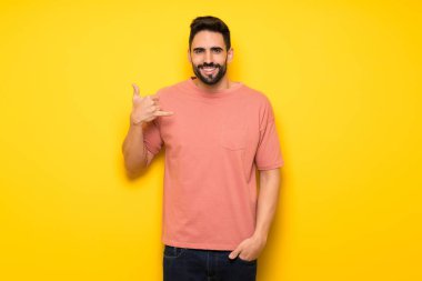 Yakışıklı adam telefon jest yaparak sarı duvarın üzerinden. Bana arka işareti de