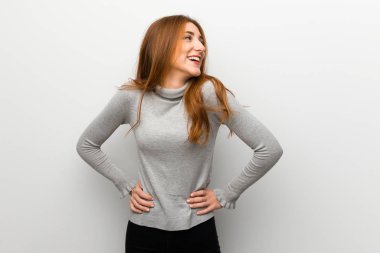 Kızıl saçlı kız kalça, silah ile poz ve gülerek beyaz duvar üzerinde