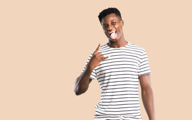 Çizgili gömlekli kamera komik göz olması ve boynuzları izole koyu sarı zemin üzerine yaptırmayı Dil Gösterilen ile adam koyu tenli