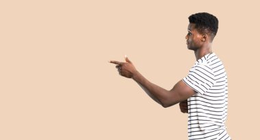 Parmak tarafına işaret ve lateral pozisyonda izole koyu sarı zemin üzerinde bir ürün sunma çizgili gömlek ile adam koyu tenli