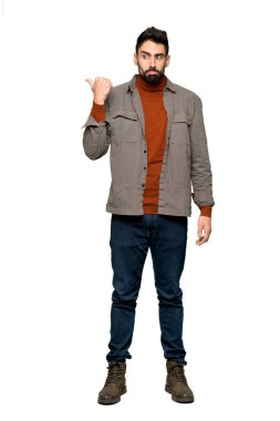 Mutsuz ve izole beyaz zemin üzerine yanına işaret eden sakallı yakışıklı adam tam uzunlukta atış