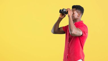 Genç Afro-Amerikan adam ve seyir için bir şey uzaktan dürbünle arka plan sarı