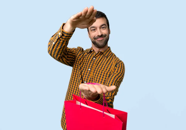 ショッピング袋を持って Copyspace 分離青の背景に広告を挿入する男 — ストック写真