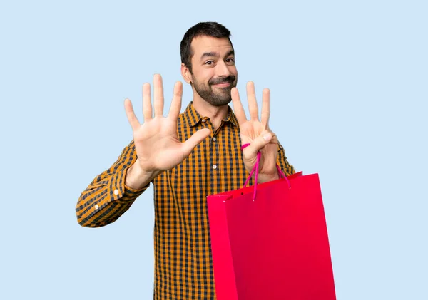 Man Shopping Bags Counting Eight Fingers Isolated Blue Background — Stock Photo, Image