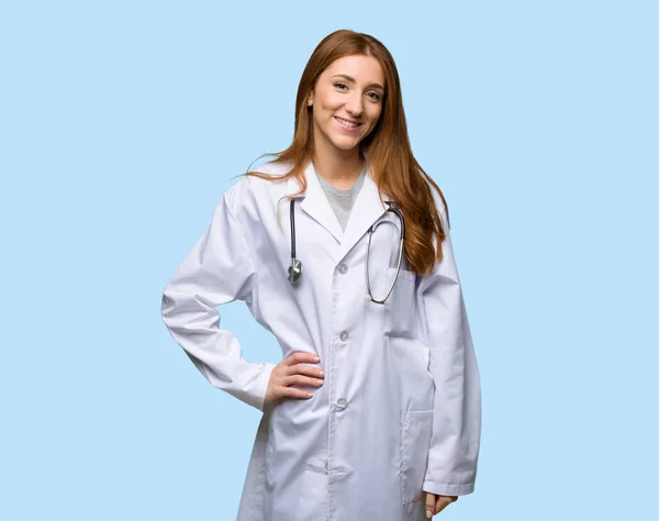 Ruiva Médico Mulher Posando Com Braços Quadril Sorrindo Fundo Azul — Fotografia de Stock