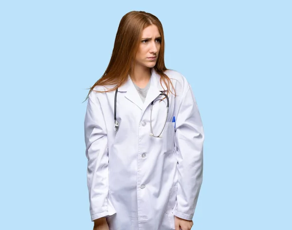 红发医生妇女感觉不安在孤立的蓝色背景 — 图库照片