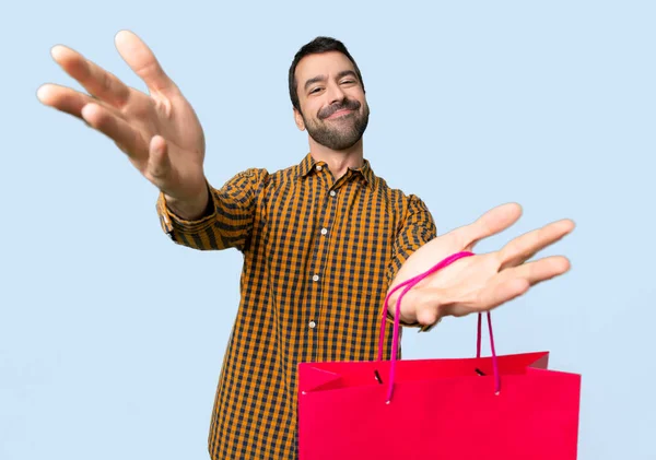 Man Shopping Bags Presenting Inviting Come Hand Isolated Blue Background — Stock Photo, Image