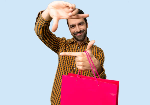 Man Met Boodschappentassen Gericht Gezicht Framing Symbool Geïsoleerde Blauwe Achtergrond — Stockfoto