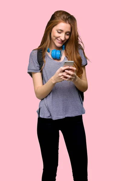 Redhead Student Žena Odesláním Zprávy Mobilním Telefonem Izolované Růžové Pozadí — Stock fotografie