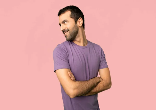 英俊的男人看着肩膀与一个微笑在孤立的粉红色的背景 — 图库照片