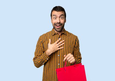 Adam alışveriş torbaları ile şaşırttı ve hemen aramaya mavi arka plan izole iken şok