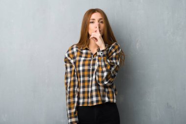 Bir işaret parmağını ağzına koyarak sessizlik jest gösteren grunge duvarın üzerinden genç Kızıl saçlı kız