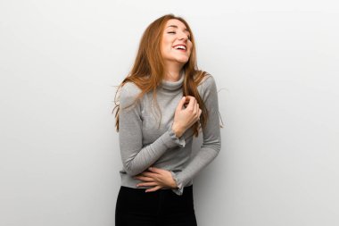 Kızıl saçlı kız beyaz duvar çok giyerken gülümseyen yüzünden göğsüne eller