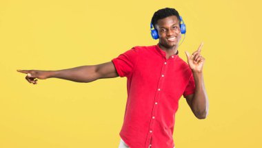 Kulaklık ile müzik dinlemek ve Sarı zemin üzerine dans Afro-Amerikan delikanlı