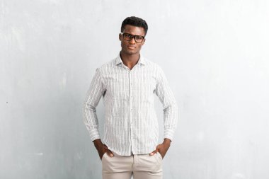 Dokulu gri duvara poz gözlüklü genç afro Amerikalı adam