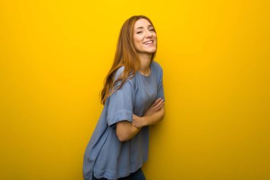 Genç Kızıl saçlı kız gülümseyerek süre geçti silah tutmak sarı duvar arka plan üzerinde