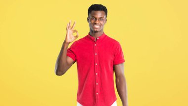 Parmaklar ok işaretiyle gösterilen genç Afro-Amerikan adam. Mutluluk ve memnuniyet sarı arka plan yüzü