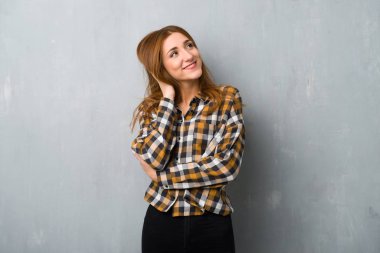 Genç Kızıl saçlı kız kafa çizilmemesi bir fikir düşünmek grunge duvarın üzerinden