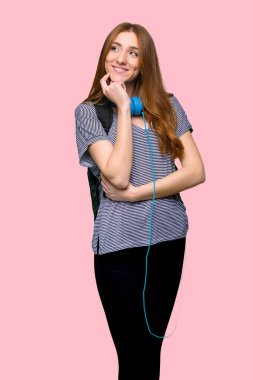 Kızıl saçlı öğrenci kadın izole pembe ararken bir fikir düşünüyorum