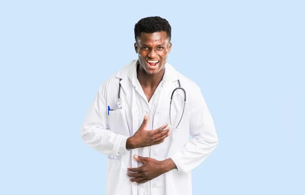 非洲裔美国医生微笑了很多 而把手放在胸部孤立的蓝色背景 — 图库照片