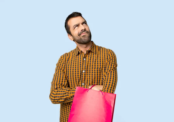 Mannen Med Shoppingkassar Tittar Upp Med Allvarliga Ansikte Isolerade Blå — Stockfoto