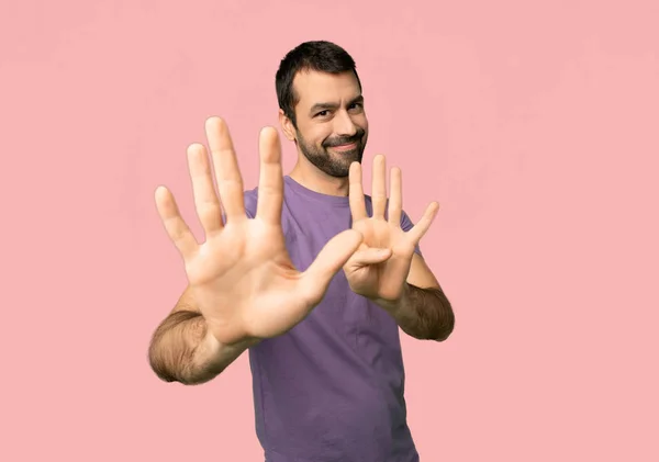 英俊的人计数九与手指在被隔绝的粉红色背景 — 图库照片