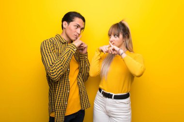 Sessizlik jest bir işaret gösteren canlı sarı arka plan üzerinde genç çift