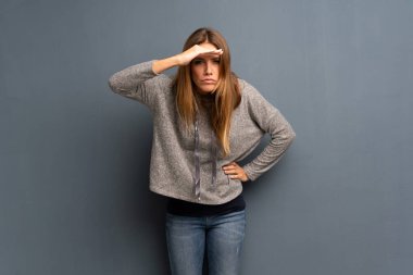 Sarışın kadın çok uzak el ile seyir gri arka plan üzerine bir şey bakmak için