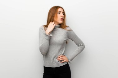 Kızıl saçlı kız yorgun ve hasta ifade ile beyaz duvar üzerinde