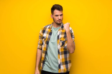 Yakışıklı adam kızgın hareketi ile sarı duvarın üzerinden